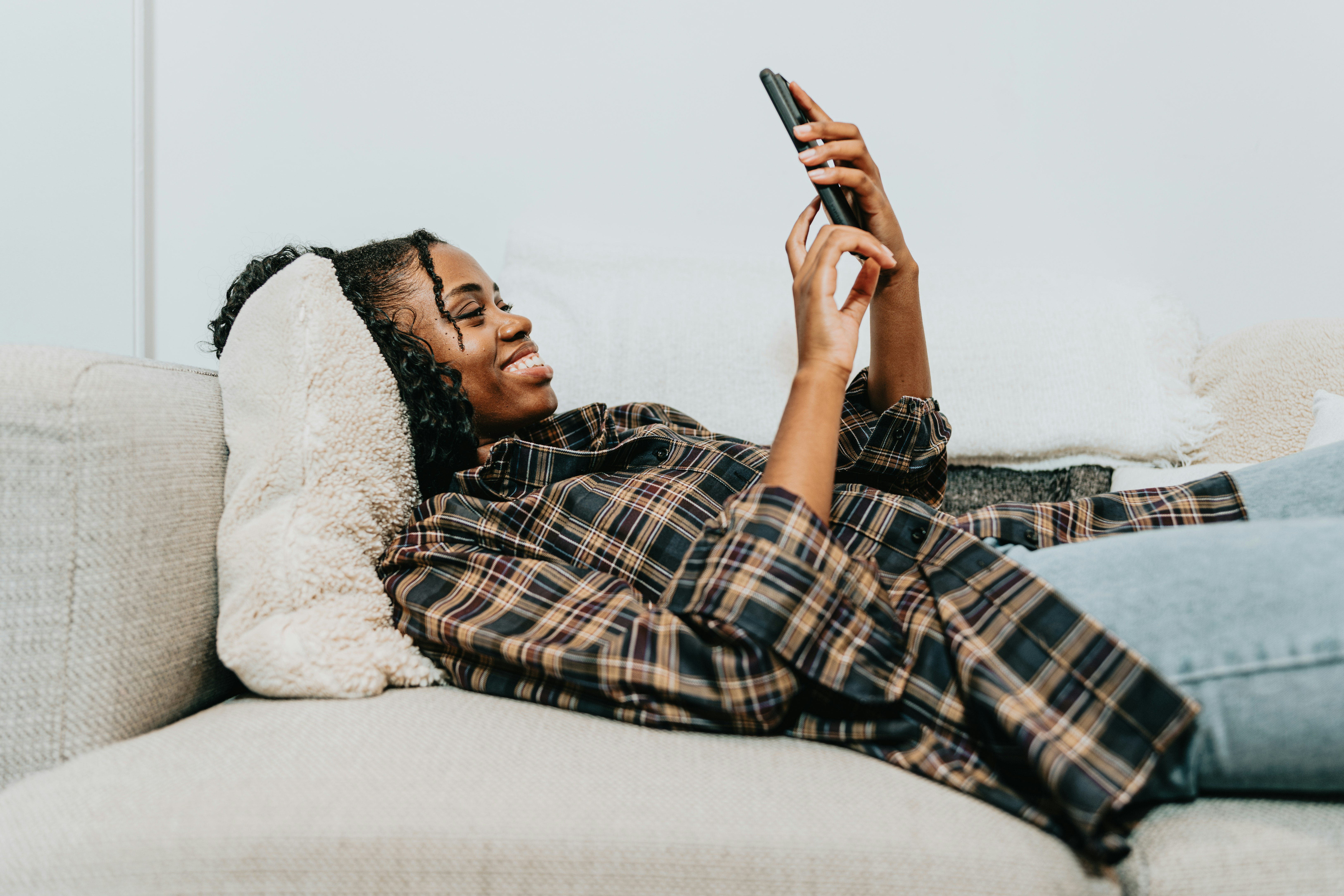 Girl smiling on couch while scrolling on phone